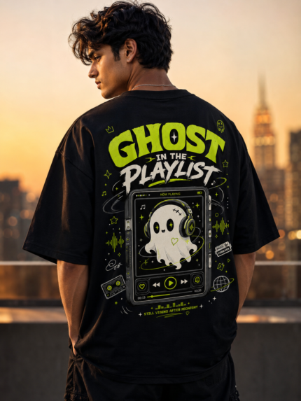 Young woman wearing VOUX black oversized cotton t-shirt with neon green Ghost in the Playlist graphic print on the back, featuring a cute ghost with headphones on a retro music player, styled in streetwear aesthetic against a city sunset backdrop
